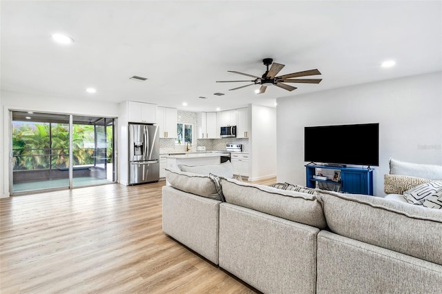 living room featuring ceiling fan and light hardwood / wood-style flooring