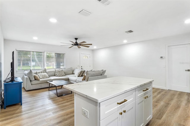 kitchen featuring light stone countertops, white cabinets, light hardwood / wood-style flooring, and ceiling fan