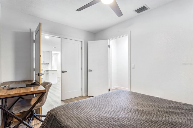 bedroom featuring a barn door, light hardwood / wood-style floors, and ceiling fan