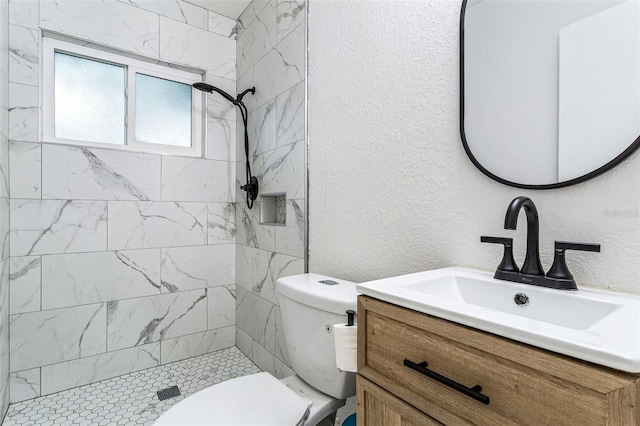 bathroom with vanity, tiled shower, and toilet