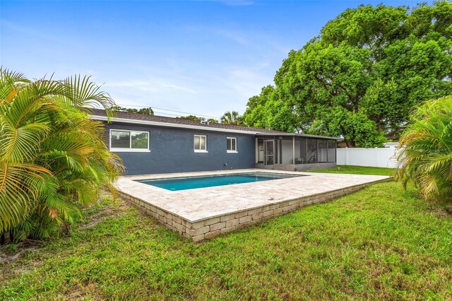 view of pool with a patio area, a lawn, and a sunroom