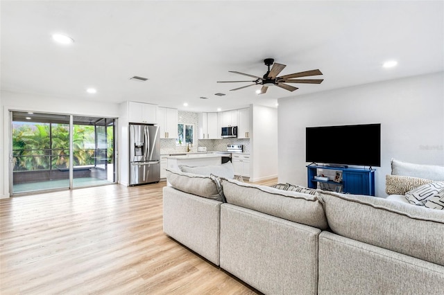 living room with light hardwood / wood-style floors and ceiling fan