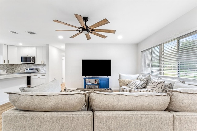 living room with light hardwood / wood-style flooring and ceiling fan