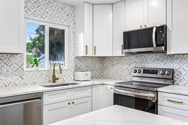 kitchen featuring white cabinets, tasteful backsplash, light stone counters, sink, and stainless steel appliances