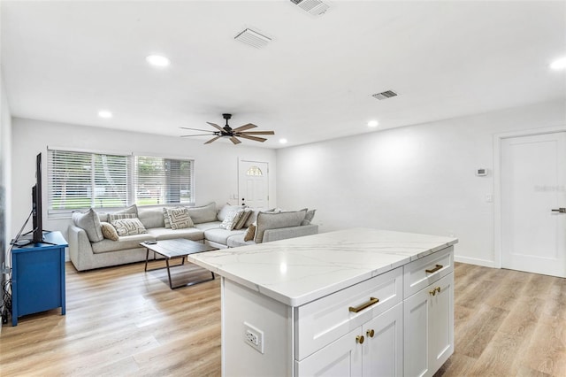 kitchen with white cabinets, light stone countertops, light wood-type flooring, and ceiling fan