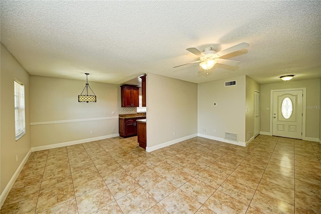 interior space featuring ceiling fan, light tile patterned flooring, and a textured ceiling