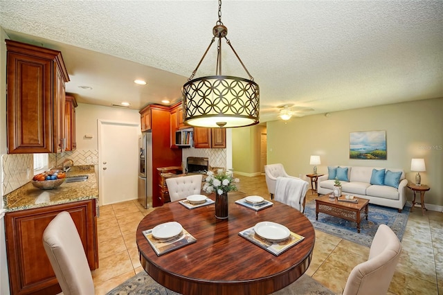 tiled dining room with ceiling fan, sink, and a textured ceiling