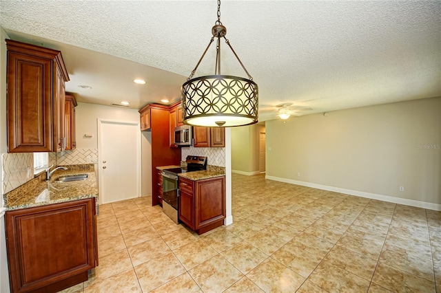 kitchen featuring appliances with stainless steel finishes, light stone counters, pendant lighting, and sink