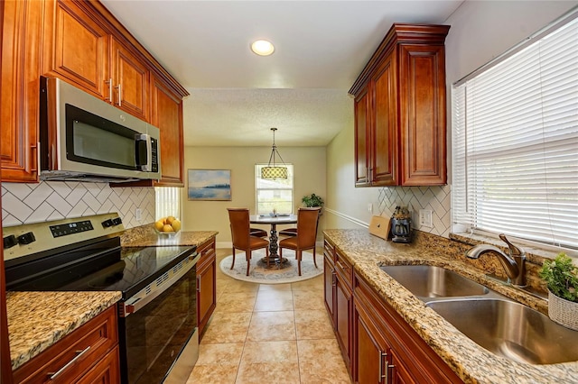 kitchen with backsplash, stainless steel appliances, sink, pendant lighting, and light tile patterned flooring