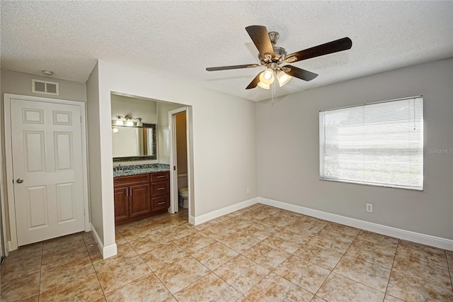 unfurnished bedroom with connected bathroom, ceiling fan, sink, a textured ceiling, and light tile patterned floors