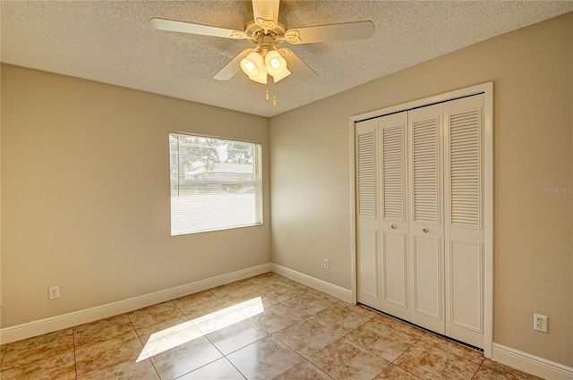 unfurnished bedroom with ceiling fan, a closet, light tile patterned floors, and a textured ceiling