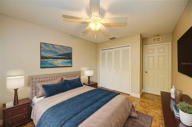 bedroom featuring a textured ceiling, a closet, ceiling fan, and light tile patterned flooring