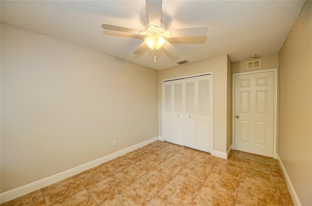 unfurnished bedroom featuring ceiling fan, light tile patterned floors, a textured ceiling, and a closet