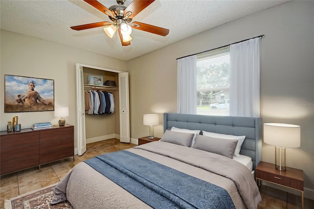 tiled bedroom with ceiling fan, a textured ceiling, and a closet