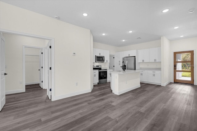 kitchen with appliances with stainless steel finishes, white cabinetry, a kitchen island with sink, and wood-type flooring