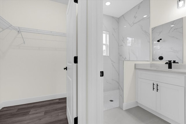 bathroom featuring tiled shower, wood-type flooring, and vanity