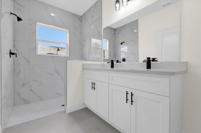 bathroom with tiled shower, tile patterned flooring, and vanity