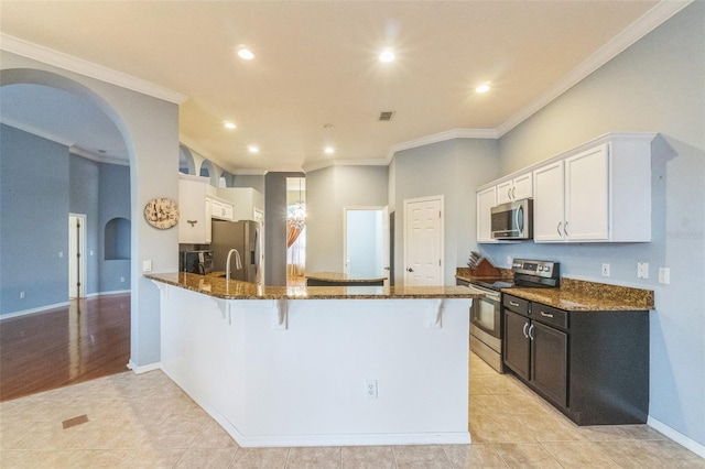 kitchen with white cabinetry, ornamental molding, light tile patterned flooring, kitchen peninsula, and stainless steel appliances