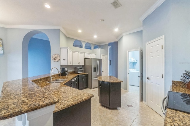 kitchen featuring white cabinetry, a center island, sink, stainless steel appliances, and washer / clothes dryer