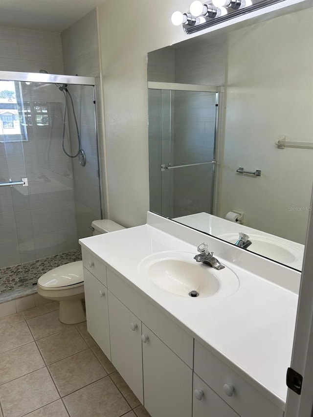 bathroom featuring vanity, toilet, tile patterned flooring, and a shower with door