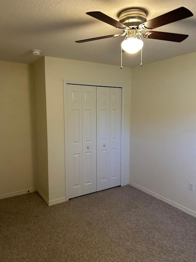 unfurnished bedroom with carpet flooring, a textured ceiling, a closet, and ceiling fan