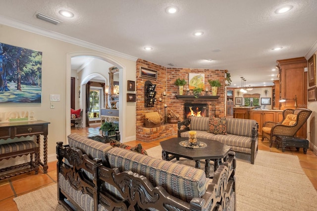 living room with light tile patterned floors, ornamental molding, a textured ceiling, and a brick fireplace