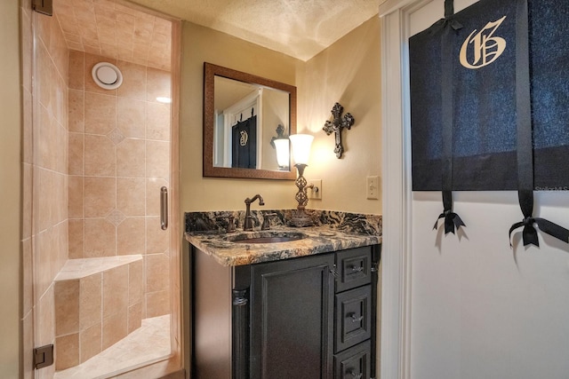 bathroom featuring vanity, a textured ceiling, and a shower with door