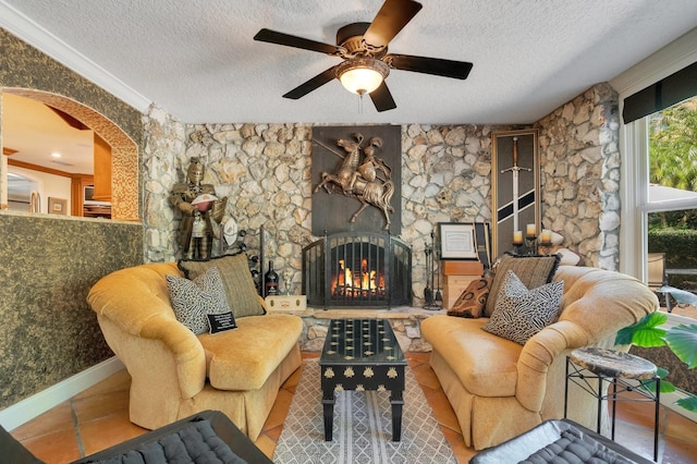 living area featuring ornamental molding, a textured ceiling, a fireplace, and ceiling fan