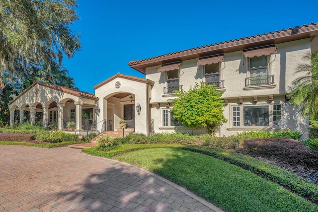 mediterranean / spanish home with a balcony and a front yard