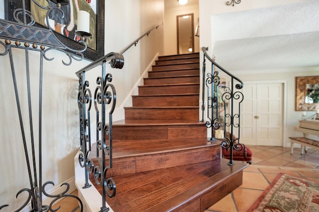 stairs with ornamental molding and tile patterned flooring