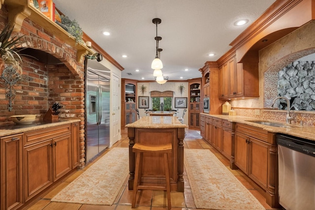 kitchen featuring sink, a kitchen island, pendant lighting, built in appliances, and ornamental molding