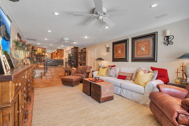 living room with ceiling fan, a textured ceiling, light tile patterned floors, and ornamental molding