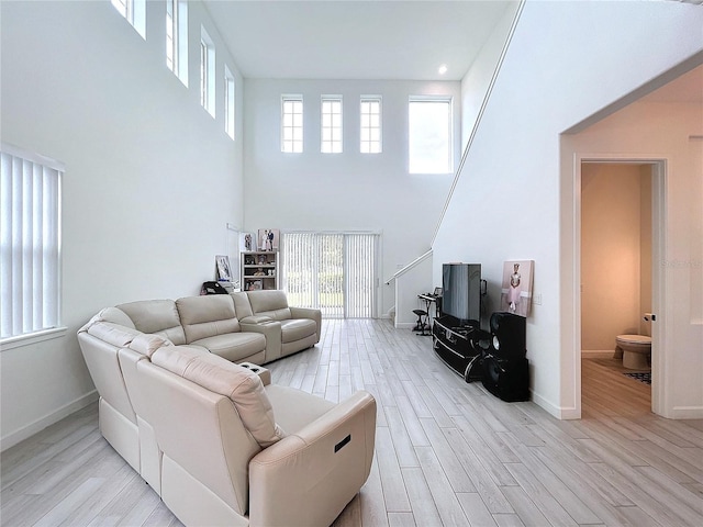 living room featuring light hardwood / wood-style floors, a towering ceiling, and plenty of natural light