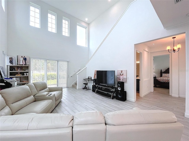 living room with a healthy amount of sunlight, a towering ceiling, wood-type flooring, and an inviting chandelier