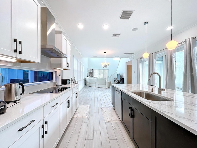 kitchen with wall chimney exhaust hood, sink, white cabinets, and hanging light fixtures