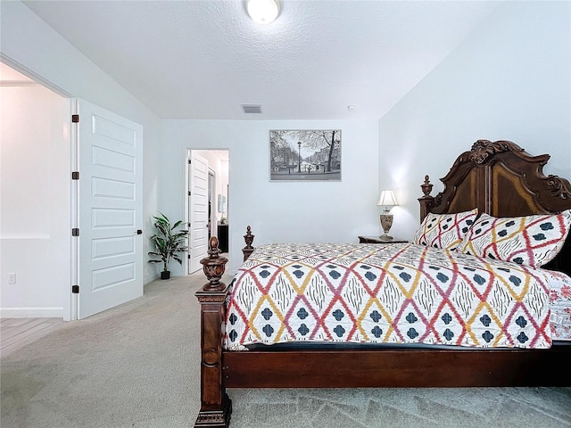 bedroom featuring a textured ceiling and light colored carpet