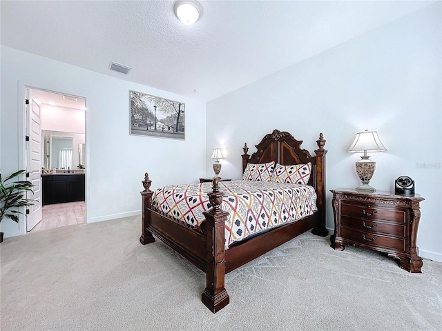 carpeted bedroom featuring a textured ceiling and ensuite bathroom