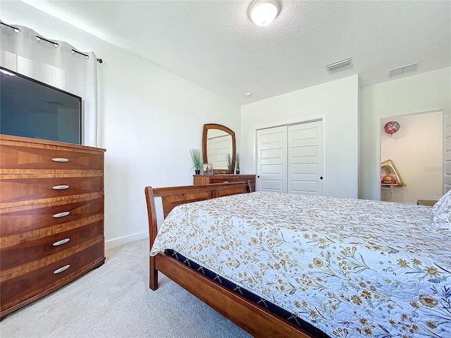 bedroom featuring light carpet, a textured ceiling, and a closet