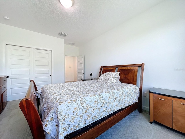 bedroom with a closet, light carpet, and a textured ceiling