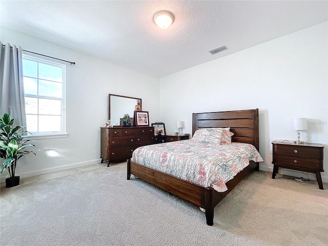 bedroom with a textured ceiling and light colored carpet