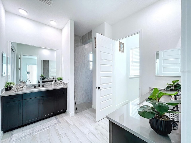 bathroom with a tile shower, hardwood / wood-style flooring, and vanity