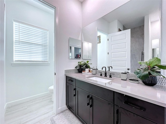 bathroom with toilet, vanity, and wood-type flooring