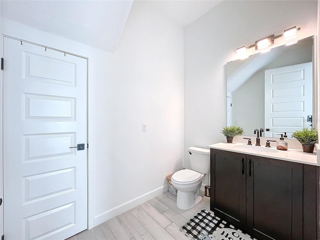 bathroom with vanity, hardwood / wood-style floors, vaulted ceiling, and toilet