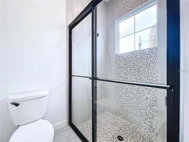 bathroom featuring toilet and a shower with shower door