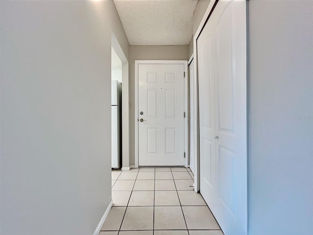 corridor featuring light tile patterned floors and a textured ceiling