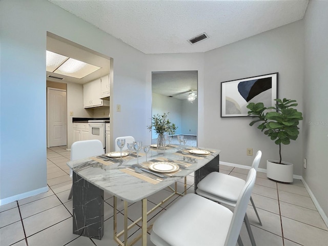 dining space featuring ceiling fan, light tile patterned flooring, and a textured ceiling