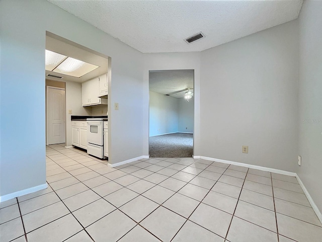 kitchen featuring a textured ceiling, white range, ceiling fan, white cabinetry, and light tile patterned flooring