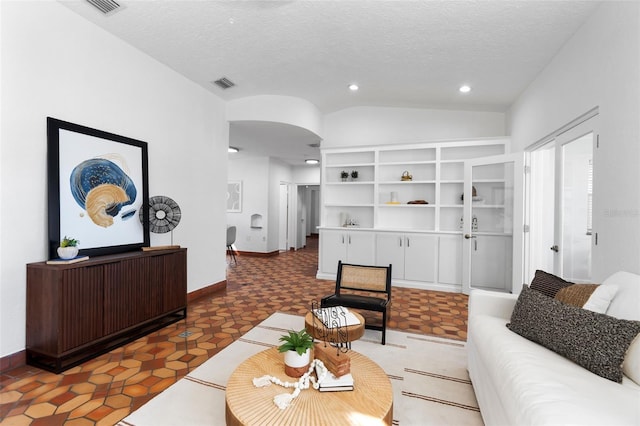 living room with lofted ceiling, a textured ceiling, and dark tile patterned floors