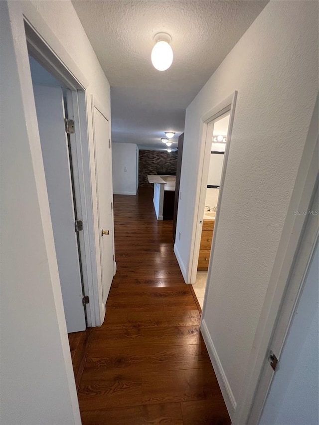 hallway featuring a textured ceiling and dark hardwood / wood-style flooring