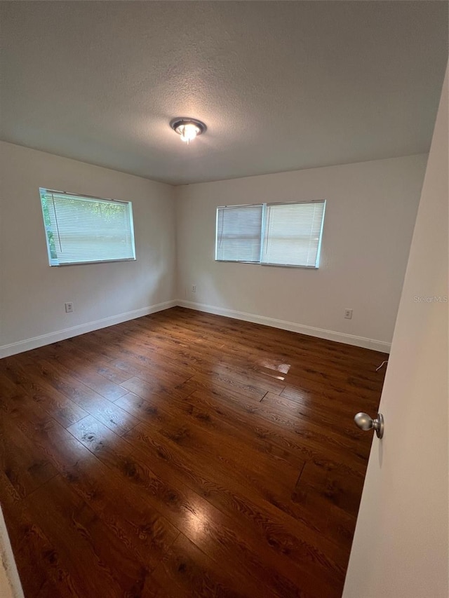 unfurnished room with dark wood-type flooring and a textured ceiling